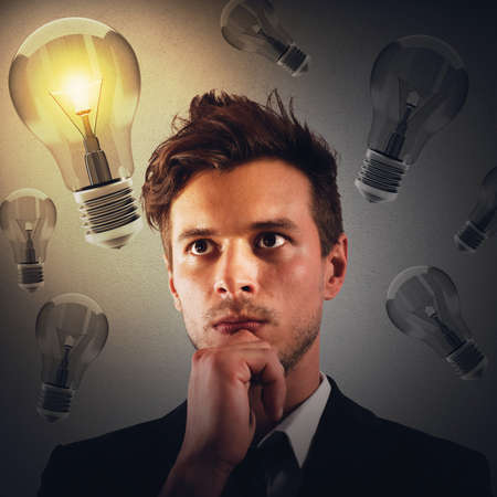 Man with thoughtful expression with bulbs backgroundの写真素材
