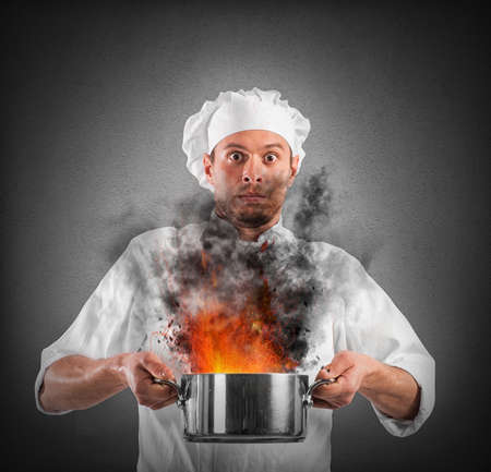 Chef shocked holding a pot with flamesの写真素材
