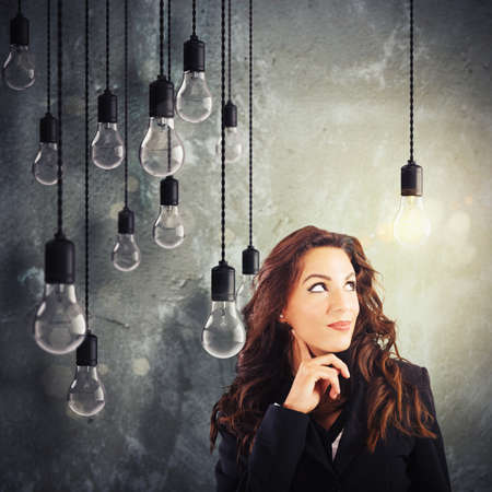 Woman with lit lightbulb among unlit bulbs