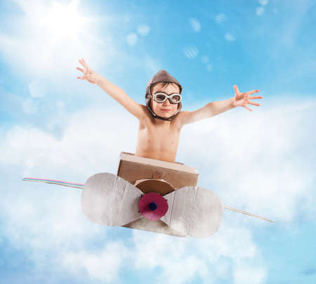 Child with cardboard airplane in the skyの写真素材
