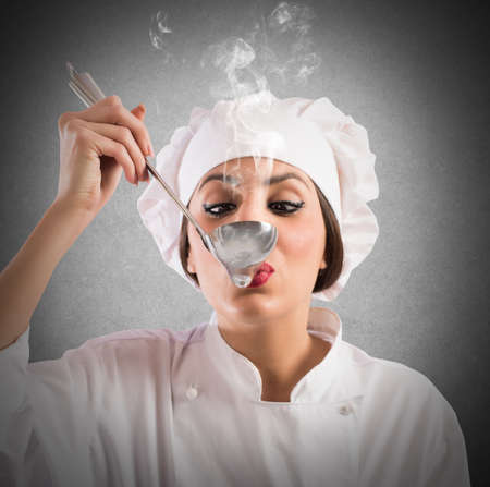 Woman taster chef tastes a steaming ladleの写真素材