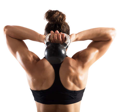 Muscular woman from behind trains with kettlebellの写真素材