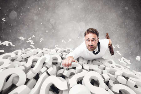 Afraid businessman clinging to question marks pile