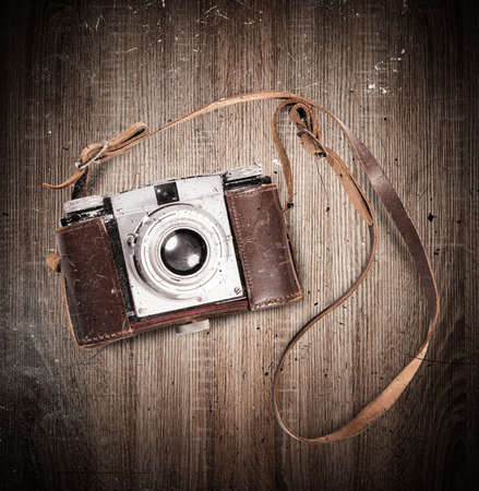 Vintage camera with leather belt on wooden background