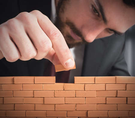 Businessman building a wall with small bricksの写真素材