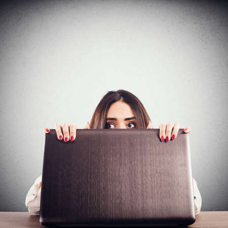 Woman hidden behind the computer screen peeks secretly