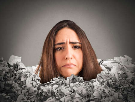 Sad woman trapped in a mountain of paperworkの写真素材