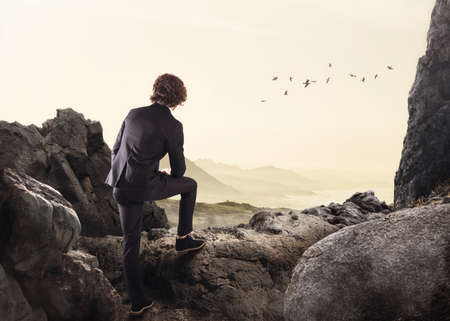 Businessman leaning on a rock watching the horizonの写真素材