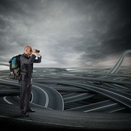 Businessman with backpack and binoculars watching a tangle of streets