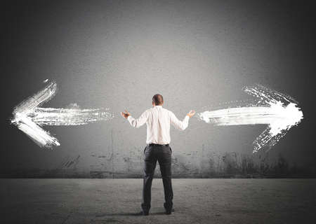 Businessman in front of a choice with arrows in opposite directionsの写真素材