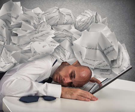 Businessman with a pile of sheets over his headの写真素材