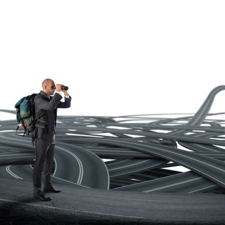 Businessman with backpack and binoculars watching a tangle of streetsの写真素材