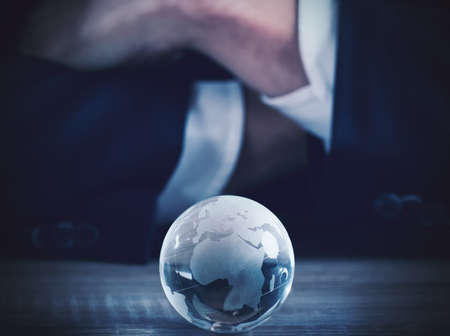Businessman with world glass sphere with continents on the tableの写真素材