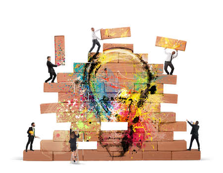 Business person built together a big brick wall with drawn lightbulbの写真素材