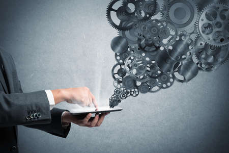 Businessman touch a tablet screen with gears mechanism