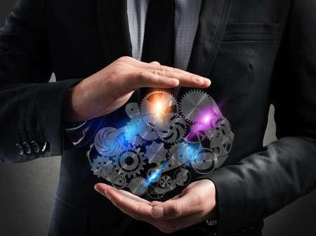 Businessman holds in his hands a system of a gear mechanismの写真素材