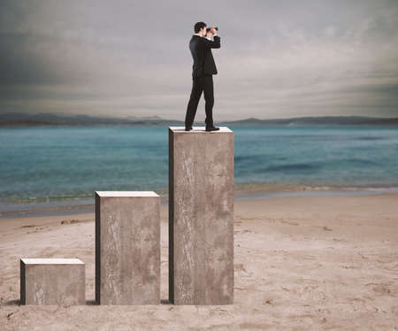 Businessman looks at the economic future with binoculars over a statisticの写真素材