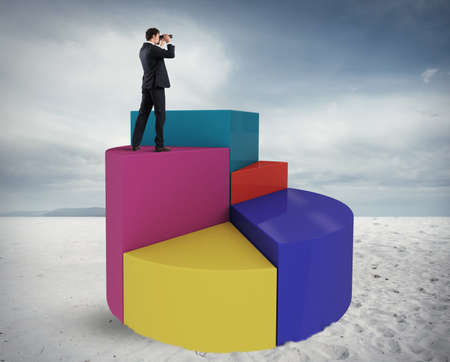 Businessman looks at the economic future with binoculars over a graphの写真素材