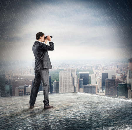 Businessman looks at the city from the roof with binocularsの写真素材