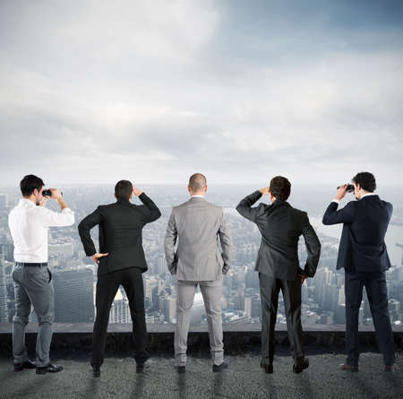 Businessmen looks at the city from the roof with binocularsの写真素材