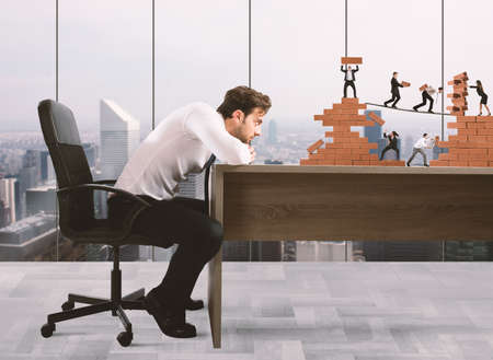 Businessman watches a teamwork of businesspeople work together to a bricks constructionの写真素材