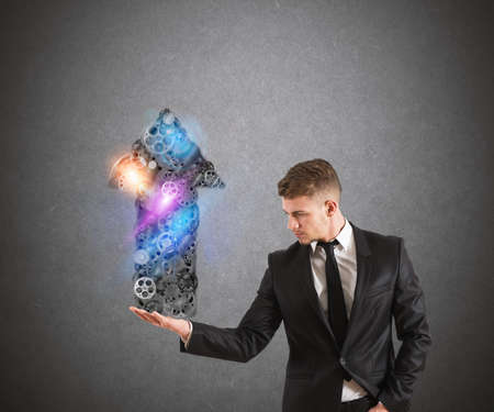 Businessman holds a system of gears that form an arrowの写真素材