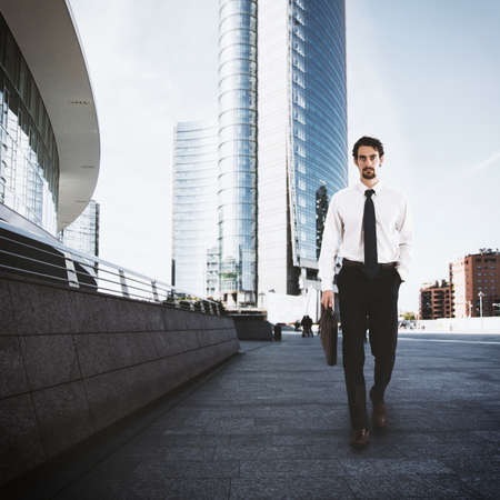 Businessman walking on the street with skyscraper backgroundの写真素材