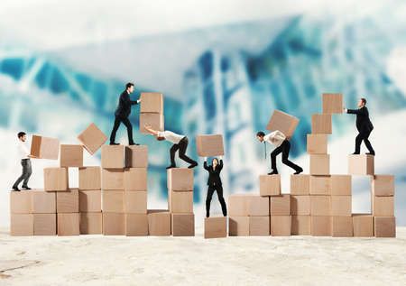 Team of businesspeople build a construction with wood cubesの写真素材