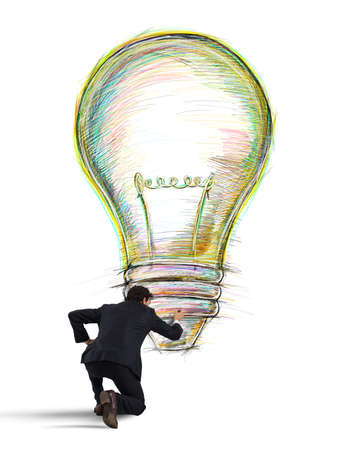 Businessman draws on the wall a big colored bulb with bright colorsの写真素材