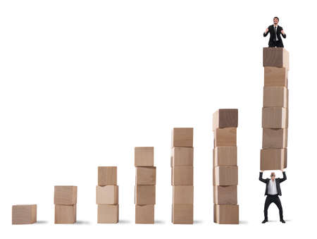 Businessman rejoices on the last step of the statistical lifted by a colleagueの写真素材