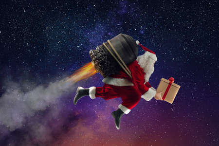 Santa Claus with gift box flies with a missile in a spaceの写真素材