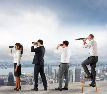 Business people looks at the city from the roof with binocularsの写真素材