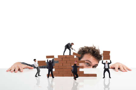 Businessman watches a teamwork of businesspeople work together by building a brick wallの写真素材