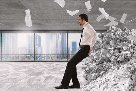 Businessman pushing with fatigue a big pile of paperworkの写真素材
