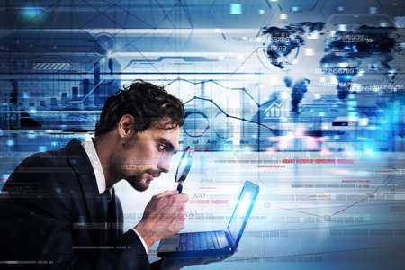 Businessman watching with magnify lens a laptop monitorの写真素材