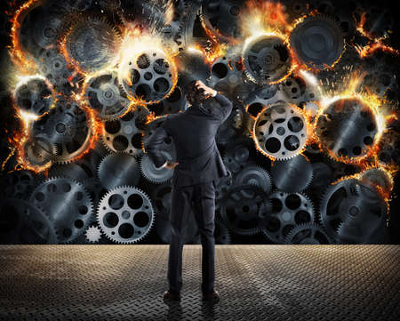 Stress concept with overworked businessman desperately looks a gear mechanism burnの写真素材