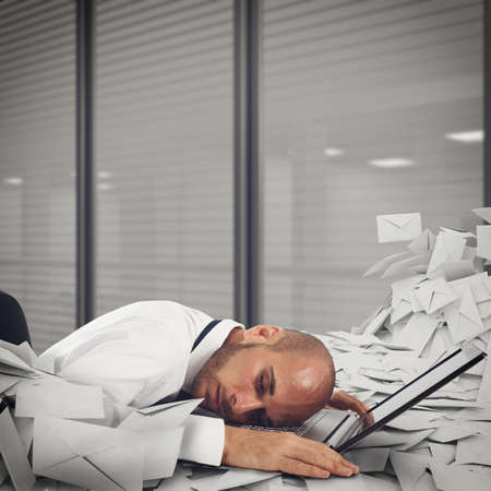 Businessman on laptop with a pile of worksheets and mail. Buried by work concept