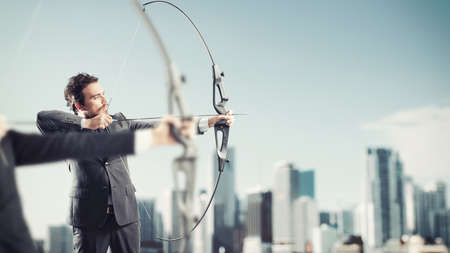 Businessmen in a competition with the arc and arrows to reach and hit new targets in a roof of skyscraperの写真素材
