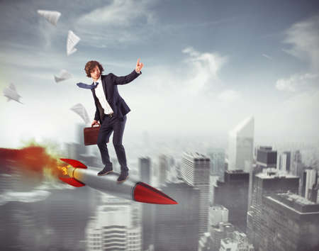 Businessman flying on a rocket over the city. Increase the climb to success conceptの写真素材