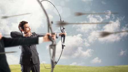 Businessmen in a competition with the arc and arrows to reach and hit new targetsの写真素材
