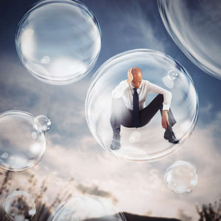Sad businessman flies in a bubble. isolate themselves inside a bubble detachment from the outside world conceptの写真素材