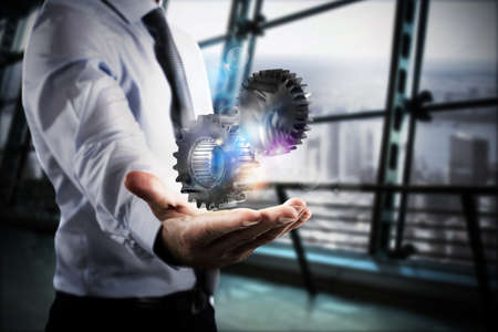 Businessman holds in his hand a system of a gear mechanismの写真素材