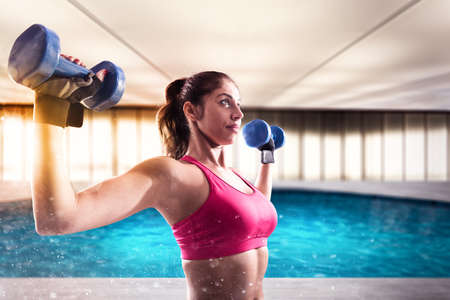 Muscular woman is training with weights dumbbells