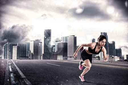 Athletic woman runner on the asphalt of a city roadの写真素材
