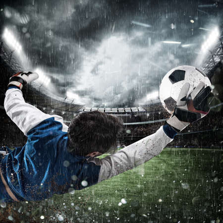 Goalkeeper catches the ball in the stadiumの写真素材