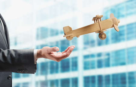 Businessman holding a small wooden aircraft. Startup working enterprise conceptの写真素材