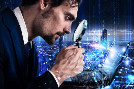 Man looks at the magnifying glass a laptop. Concept of software analysis