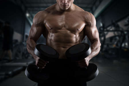 Athletic man training biceps at the gymの写真素材