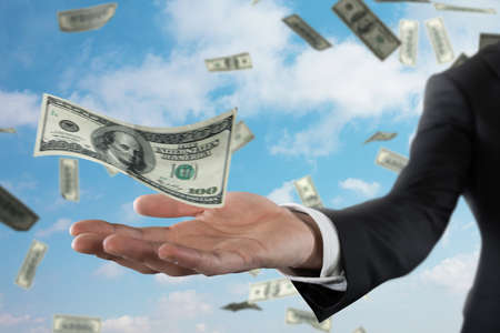 Businessman with rainy banknotes over sky background. Concept of success, career and big incomeの写真素材