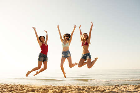 Happy smiling friends jumping at the beachの写真素材